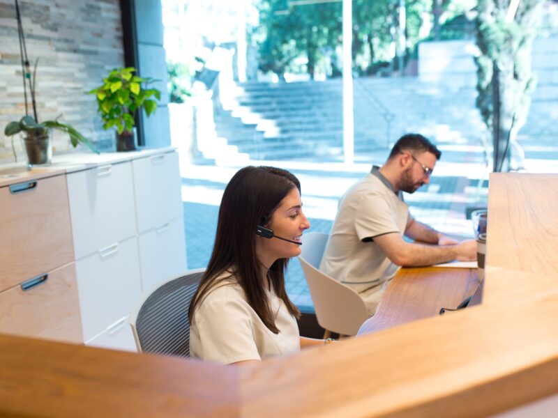 Two,Receptionists,Working,At,The,Front,Desk,Of,A,Physiotherapy